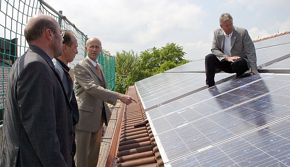 Herr Jochen Pauli erklärt Landrat Gerhard Bauer und Herrn Werner Schmidt die Photovoltaikanlage auf einem Hausdach.